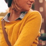 Close up of a woman in a yellow sweater. 