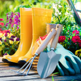 Close up of garden boots and tools outside.