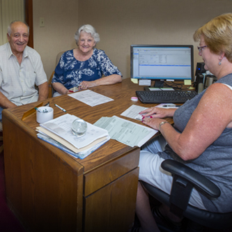 Senior couple sitting at the desk of a team member from Cayuga Lake National Bank.